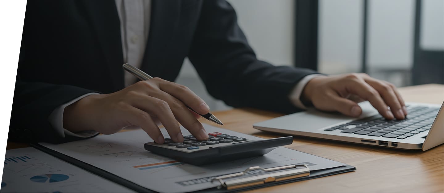 デスク上で、電卓とノートパソコンを使って作業をするビジネスパーソンの手元。